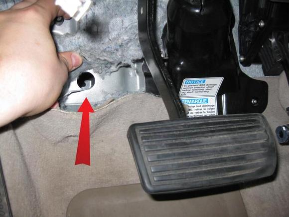 This is a shot of the firewall location where I ran the 4g power wire.  When researching running through the firewall I noticed everyone was having a lot of difficulty with it.  So, I figure posting this may help someone.  Instead of drilling holes, simply locate this stock opening.  Through this opening the wire doesn't go straight into the engine bay, but rather it goes into a frame rail and after a few inches exits to the right into the engine bay.  The hole on the engine bay side is slightly smaller, so anything larger than 4g may not clear it with room for a rubber grommet.  The wire in the photo is just the wire used to fish the 4g wire.