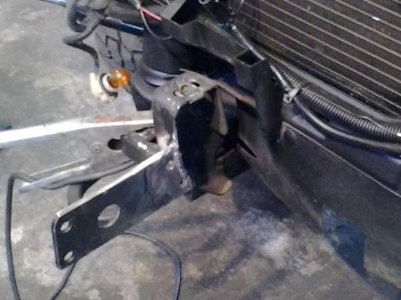 Welded mount to front of frame rails and cut slits into the spoiler to pass through. It doesnt get more rigen than this.