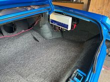 The carpeted trunk floor and the 8-channel amp.  The amp is mounted to a 1/2" piece of plywood that I screwed to the metal "fin" that hangs down where the 