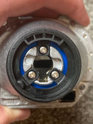 Here the Moto-Holder base is screwed onto the projector housing. Note the slot for the ground rod of the bulb to pass through. Also note the dimple at 7 or 8 o'clock to mate w/ the horseshoe clip.