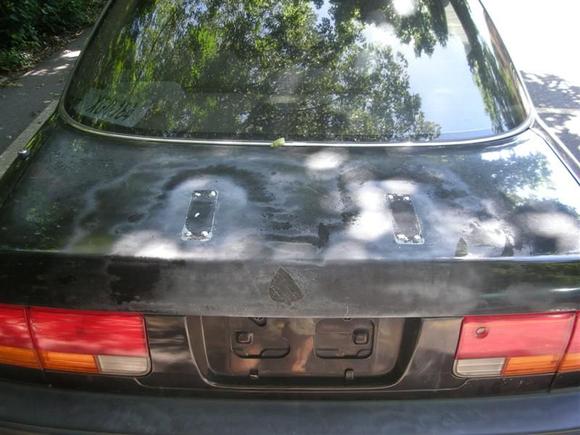 Rear where an old spoiler has been removed leaving holes and cracks in the trunk.