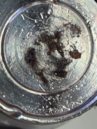 Solenoid debris on top of PCS end for scale, aluminium background about 10mm in diameter