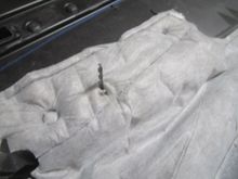 Showing opened hole through factory door panel insulator pad after drilling