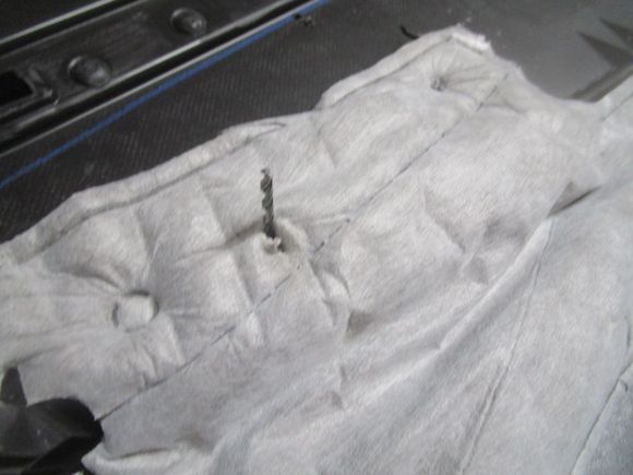 Showing opened hole through factory door panel insulator pad after drilling