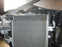 Left side condenser and radiator.  Note the debris on radiator at top right and also lower right.  With the bumper in place you will not see this.  Condenser has ears on inboard side that drop into slots on the radiator, then secured by a single screw.  When released, condenser can be moved forward enough for cleaning.