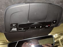 You want to slide a credit card in the upper left/right (of this picture) between the headliner and the plastic housing