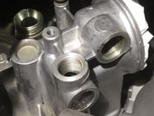 oil filter housing showing cooler line connections. one has 22/26 adapter and other connection is the furthest on the right with 22/26 removed. 