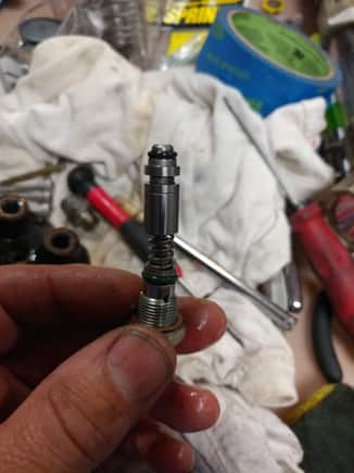 This is the pressure regulator assembly. Make sure the pointed end comes out when you remove the screw - the crid would be trapped there. You can get it with a small magnet retriever if it's stuck.
