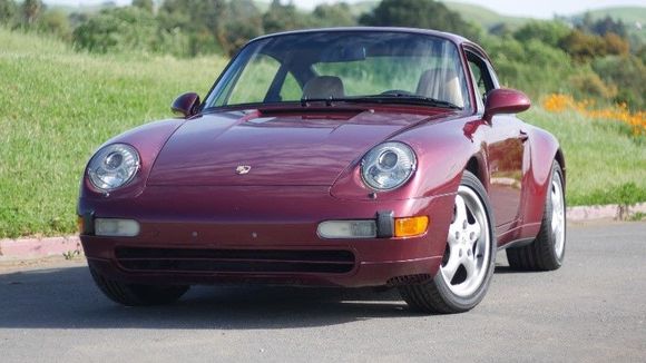 This 1996 Porsche 911 Carrera 4 coupe is shown in Arena Red over a cashmere leather interior and is powered by a 3.6 liter flat six paired with a six-speed manual transaxle and all-wheel drive.