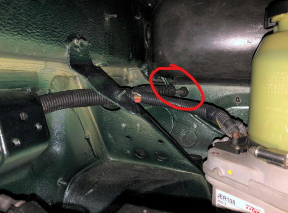 Location where hydraulic supply line was snaked through firewall at existing grommet on passenger side of frunk

