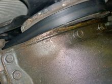 Front of oil pan with gasket poking out. Not touching balancer even though it looks like it in this pic. Can see coolant leak made its way to bottom of balancer and drips from gasket. THINK it's coming from radiator bottom hose clamp.  Yuk.