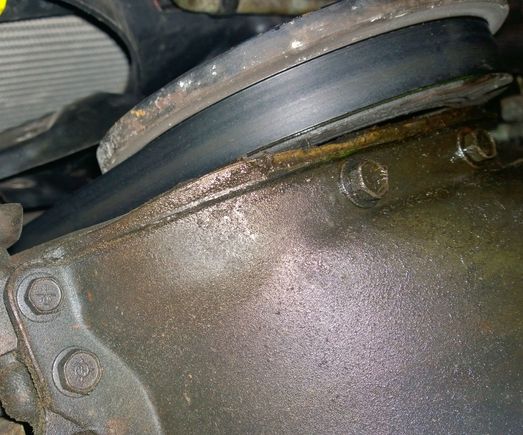 Front of oil pan with gasket poking out. Not touching balancer even though it looks like it in this pic. Can see coolant leak made its way to bottom of balancer and drips from gasket. THINK it's coming from radiator bottom hose clamp.  Yuk.