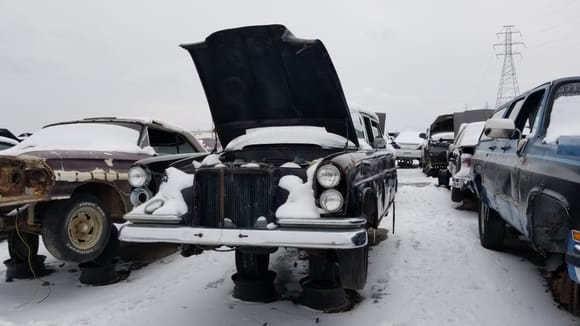 It seems like some kind of 1959–1968 Mercedes W111. This one is especially dreadful to see at the junkyard, even in this condition, it is still worth restoring, since it is extraordinary rare, and it still has its engine and interior remnants in place...