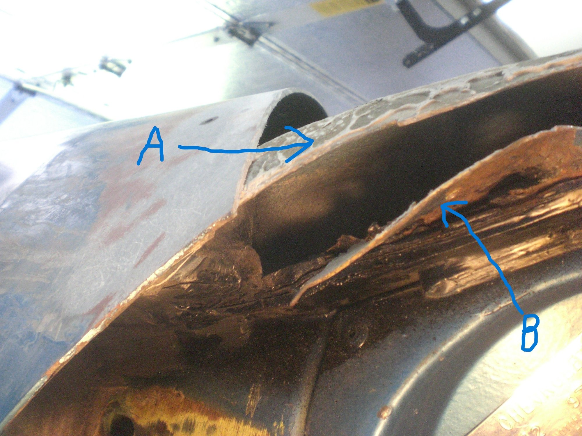 This view angle shows the vertical(ish) bonding surface (A) of the support piece.  Item B is the side edge of the metal outer corner that in this shot has been bent down & outward so I could better visualize the structure and rust damage.