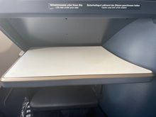 Serving table comes out from the front. It is adjustable allowing you to exit with no issues.