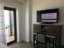 TV and dresser facing bed.  Balcony on beachfront side of hotel.