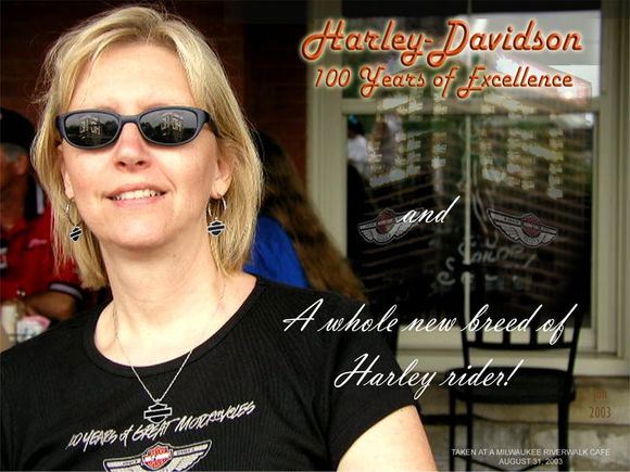 My lovely second wife 'Kea', unwittingly poses for a pseudo-poster I made for the H-D 100th. Note the 'reflections' of nearby office buildings in the glass (and glasses) which were lit up with H-D congratulatory signage during the festival. This was to be the last event we would attend together, before she went her own way, after a short, 5-year marriage! :-( (I still have the bike though! :-))