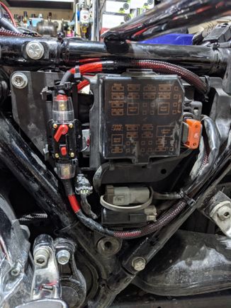 Here is a breaker style fuse with 4 gauge wire. It is tucked under the clutch side, side cover. The 4 gauge is then run up into the fairing where I installed the distribution blocks for the amps. 
