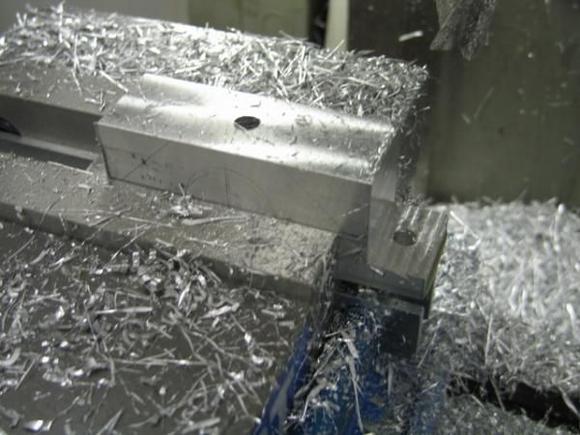 The first step is to true up a block of aluminum, measure and drill mounting holes and cut the initial flanges.