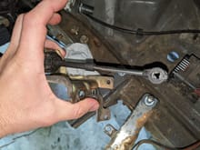 Here you can see the end of the shift linkage cable that goes onto a little rod/arm on the tranny. I had to pry the 3 little tabs with a tiny flat head in order to remove without causing damage. I struggled to find an image showing how this is held on, so I figured I'd provide it for you guys