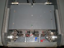 Motors mounted to sleds basically.  As the nut (red arrow) is loosened, it pushes on the back of the tank elongating the bolt which pushes the motor sled toward the front of the tank (blue arrow) taking up the slack.