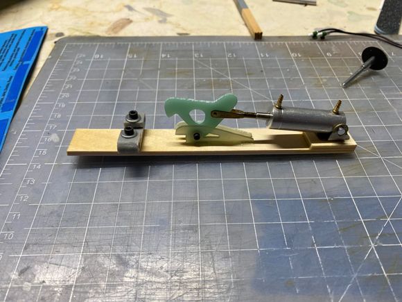 The gray clampy thing clamps to 2 CF rods that hold the chute ram, inside the chute cylinder. When the green catch is raised, allowing the gray clampy thing and the ram to shoot aft, hopefully pushing the chute into the breeze, etc...