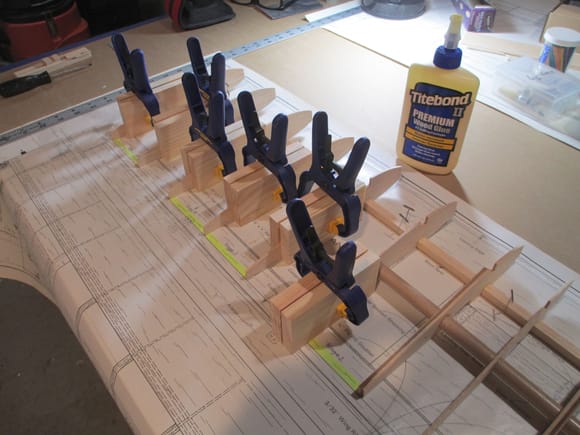 This is how I set and hold ribs into position while the glue sets.  A while ago I made these (and more) wood blocks from scraps.  They are 2" x 4" and I have a  variety in different thicknesses. 