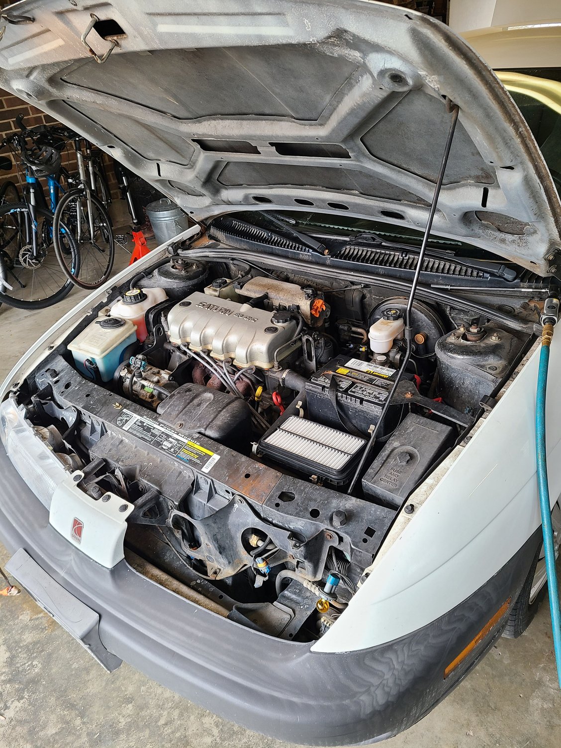 The driver side headlamp is removed, providing space to access to the condenser inlet and receiver drier hose.