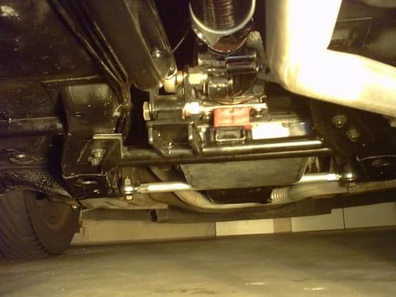 Lower firewall spreader bar to support rearward a-arm ears. transverses between  oil pan and bell housing. Also note carbon fiber driveshaft.