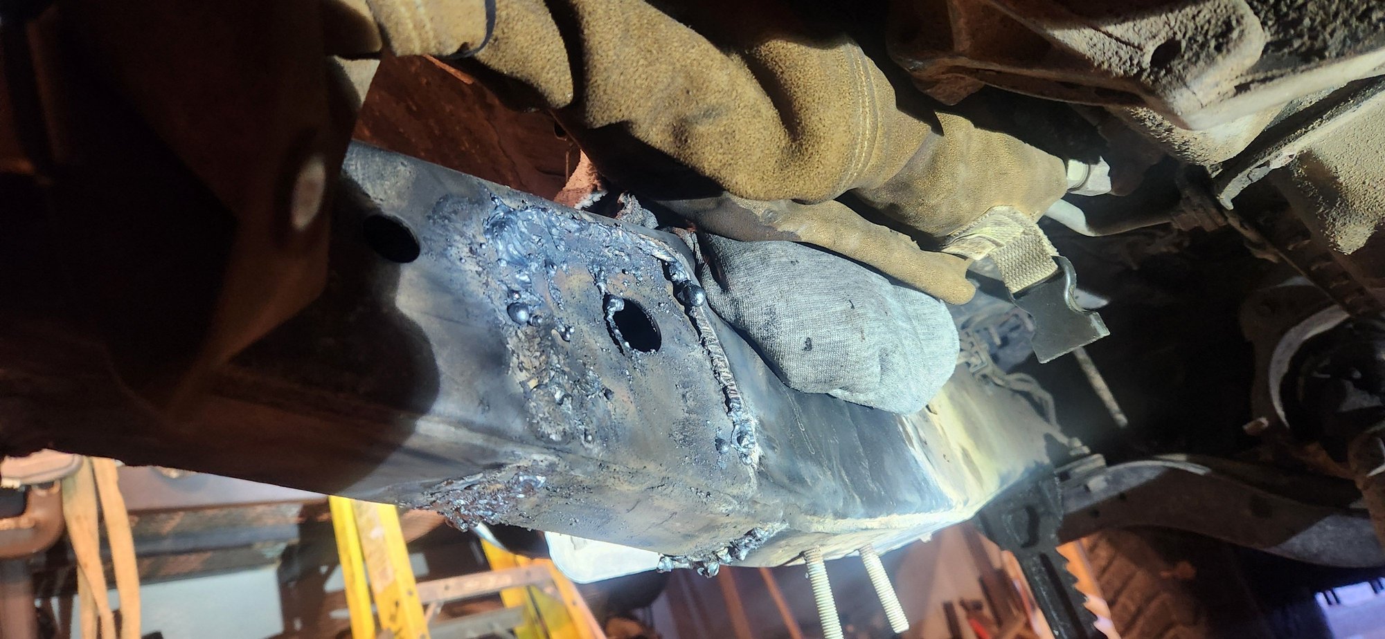 This was the most difficult spot of the entire cutting process. The gas line right next to it and the auto trans cooler lines directly above it. With the rag three times on itself and dripping wet, and the lower half of a pair of my leathers on the trans lines i was able to get in and get what i needed cut off with the torch. More that gets torched off the less grinding to do.