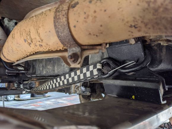 Same problem with the tranny mount, totally shot. I replaced it as well. You will notice strap. lol. The engine and tranny had moved backwards by 1/2, i thought the bad engine mounts caused it. I think lifting the suspension changed the angle and pulled the drivetrain backwards. I made my crossmember holes in stock location then had to slot them. Got to figure that out...